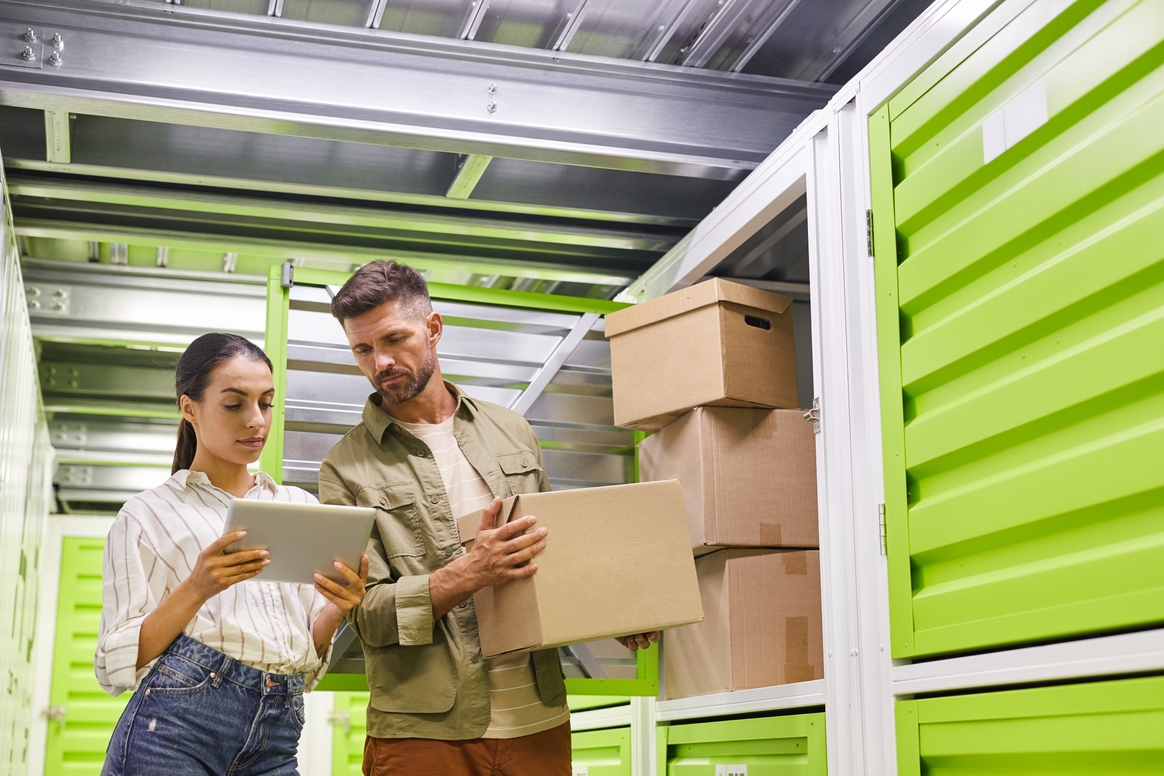 man and woman holding boxes in front of storage unit