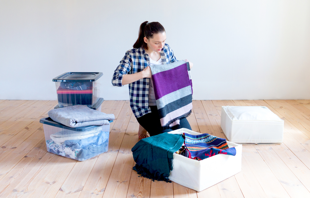 a woman decluttering her home by putting away her winter clothes into storage