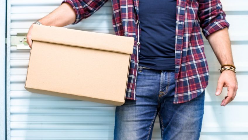 man holds box in front of shared storage unit